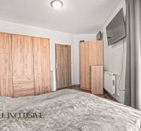 Ložnice v dvoupokojovém bytě s podlahou s dřevěným dekorem a šatními skříněmi.