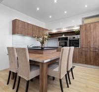 Kuchyně ve 2-pokojovém bytě s nábytkem v dřevěném dekoru a světlými stěnami.