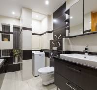 Koupelna v 2-pokojovém bytě se sprchovým koutem, pračkou a umyvadlem.