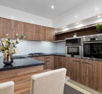 Kuchyně v 2-pokojovém bytě, dřevěný dekor, bílé obklady, vestavěné spotřebiče.