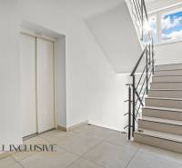 Schodiště se světlým obkladem a výtahem v 2-pokojovém bytě.