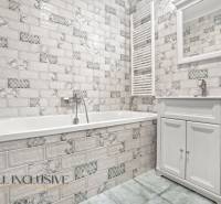 Koupelna ve vyhotovení 2pokojového bytu s bílými kachličkami a vanou.