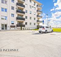 Parkoviště před bytovým domem na Panónském háji v Dunajské Stredě, s auty a travnatou plochou.