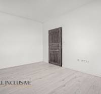 Interiér 2-pokojového bytu s bílými stěnami a podlahou s dřevěným dekorem.