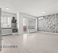 Kuchyně a obývací pokoj v 2-pokojovém bytě s podlahou s dřevěným dekorem a geometrickou stěnou.