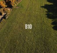 Travnatý pozemek k bydlení v Petrovicích, obklopený zelení a stromy.