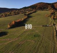 Krajina s pozemky na bydlení v Petrovicích, obklopená kopci a lesy na podzim.