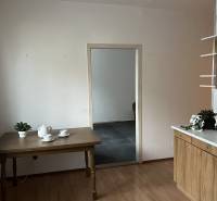 Kuchyně v 2-pokojovém bytě s podlahou v dřevěném dekoru, stolem a nádobím.