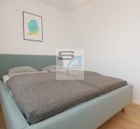 Ložnice s postelí a minimalistickou dekorací v 2pokojovém bytě, podlaha s dřevěným dekorem.