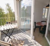 Balkon s posezením, výhled do zeleně a prosklené dveře do 2-pokojového bytu.