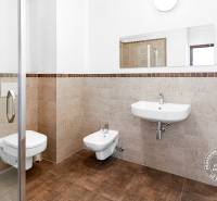 Koupelna ve 2-pokojovém bytě s toaletou, bidetem a sprchovým koutem, obložená kachličkami.