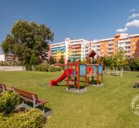 Dětské hřiště u barevných obytných budov na ulici Bosákova, ideální pro 2pokojový byt.