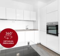 Kuchyně v 2-pokojovém bytě s bílými skříňkami, troubou a podlahou s dřevěným dekorem.