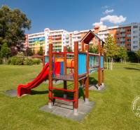 Dětské hřiště na ulici Bosákova, obklopené barevnými bytovkami a zelení.