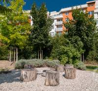 Na ulici Bosákova, barevný bytový dům, zahrada s dřevěným posezením před 2pokojovým bytem.