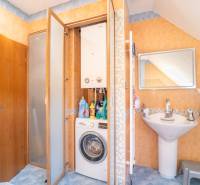 Koupelna v 2-pokojovém bytě s pračkou, plynovým kotlem a umyvadlem.