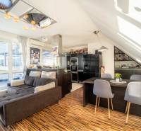 Obývací pokoj s kuchyní ve 2-pokojovém bytě s podlahou s dřevěným dekorem a pohodlnou sedačkou.