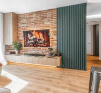 Obývací pokoj ve 3-pokojovém bytě s cihlovou stěnou, krbem a podlahou s dřevěným dekorem.