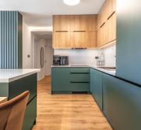 Kuchyně ve 3-pokojovém bytě s podlahou s dřevěným dekorem a zelenými skříňkami.