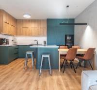 Kuchyně ve 3-pokojovém bytě s podlahou s dřevěným dekorem a jídelním stolem.