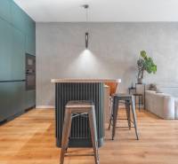 Kuchyně v 3-pokojovém bytě s ostrůvkem, kovovými židlemi a podlahou s dřevěným dekorem.