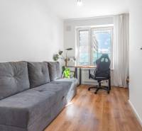 Světlý pokoj s pohovkou, kancelářskou židlí, stolem a podlahou s dřevěným dekorem.