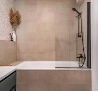 Koupelna s vanou, sprchovou zástěnou a dekorativními obklady v 3-pokojovém bytě.