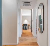 Interiér 3-pokojového bytu s podlahou s dřevěným dekorem a kulatým zrcadlem.