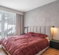 Ložnice v 3-pokojovém bytě s postelí, visícími závěsy a podlahou s dřevěným dekorem.