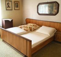 Ložnice s dřevěnou postelí, fotografiemi na stěně a zrcadlem v rodinném domě.