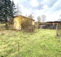 Rodinný dům v Rykynčicích, obklopený přírodou, vedle dřevěných konstrukcí a stromů.