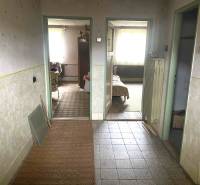 Interiér rodinného domu s chodbou a vstupem do pokojů, podlaha s dřevěným dekorem.