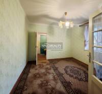 Pokoj v rodinném domě s kobercem, zelenými stěnami a dekorativním osvětlením.