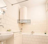 Koupelna v rodinném domě s vanou, umyvadlem a podlahou s dřevěným dekorem.