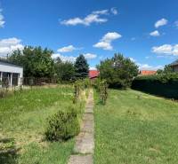 Pozemek pro bydlení na Nezvalově ulici v Bratislavě - Podunajské Biskupice obklopený zelení.