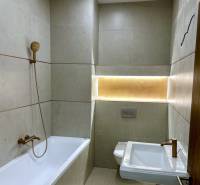 Koupelna s vanou, sprchovou hlavicí, WC a podsvícením ve 4pokojovém bytě.