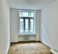 Pokoj se světlými stěnami a podlahou s dřevěným dekorem ve 4pokojovém bytě.