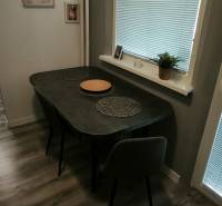 Jídelní kout v 3-pokojovém bytě s podlahou s dřevěným dekorem, s jednoduchým zařízením.