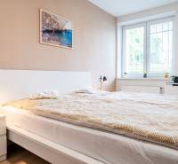 Ložnice v 3-pokojovém bytě s velkou postelí, stolními lampami a světlým interiérem.