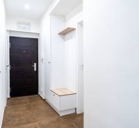 Světlá předsíň v 3-pokojovém bytě s hnědými dlaždicemi a úložným prostorem.