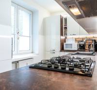 Kuchyně ve 3-pokojovém bytě s bílými skříňkami a kuchyňskou linkou s cihlovým obkladem.