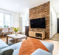 Obývací pokoj s pohovkou, stolem a TV, v 3-pokojovém bytě. Podlaha s dřevěným dekorem.