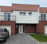 Rodinný dům v Šuranech s garáží a balkony, zaparkované auto, zatravněná plocha.