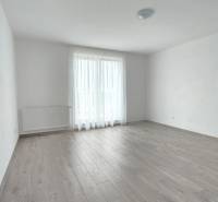 Interiér rodinného domu s podlahou s dřevěným dekorem a velkým oknem.