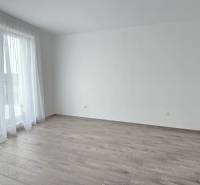 Světlá místnost v rodinném domě s podlahou s dřevěným dekorem a závěsy.