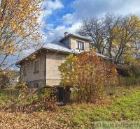 Rodinný dům v Liptovských Beharovcích uprostřed barevných podzimních stromů a keřů.