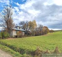 Rodinný dům v Liptovských Beharovcích obklopený přírodou a podzimními stromy na okraji louky.