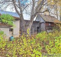 Rodinný dům v Liptovských Beharovcích obklopený podzimní přírodou, dřevěné stavby, stromy.