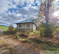 Rodinný dům v Liptovských Beharovcích obklopený přírodou, podzimní listí, obloha s oblaky.