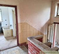 Interiér rodinného domu s obkladem, starou vanou a podlahou s dřevěným dekorem.